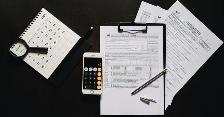A US tax form on a desk beside a laptop showing a share trading app, representing the W-8BEN for Australian investors.