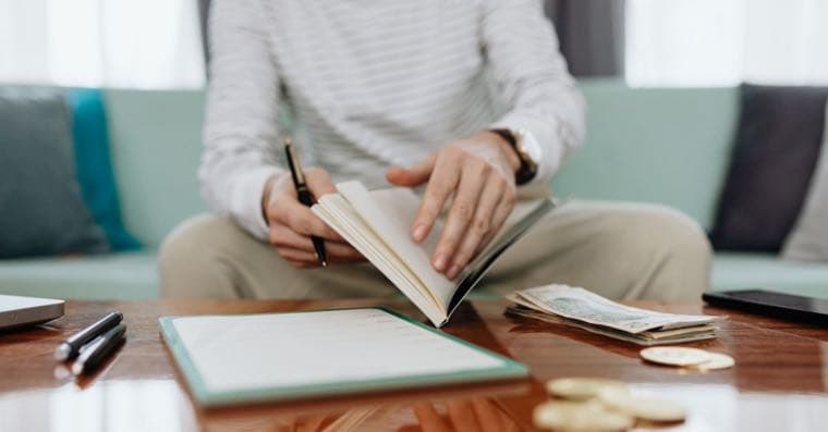 A person reviewing bills and financial statements at a kitchen table