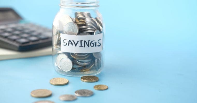 A jar of coins labelled super beside a calculator and payslip