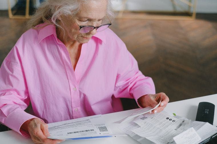 An older woman reviewing financial documents at her desk
