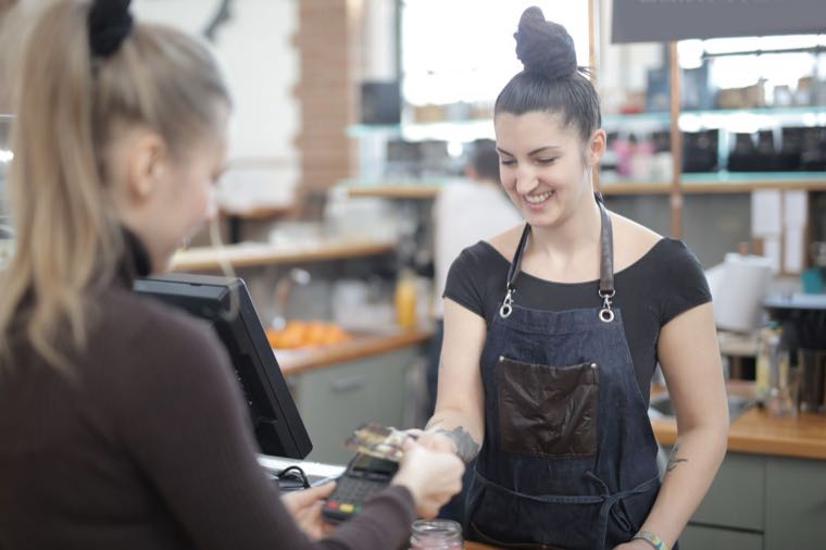 A casual retail worker helping a customer at a checkout in Australia