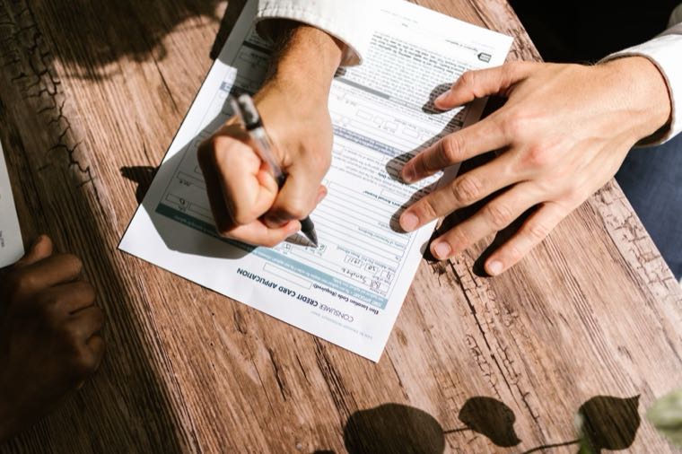 A person filling out a personal loan application form on a desk
