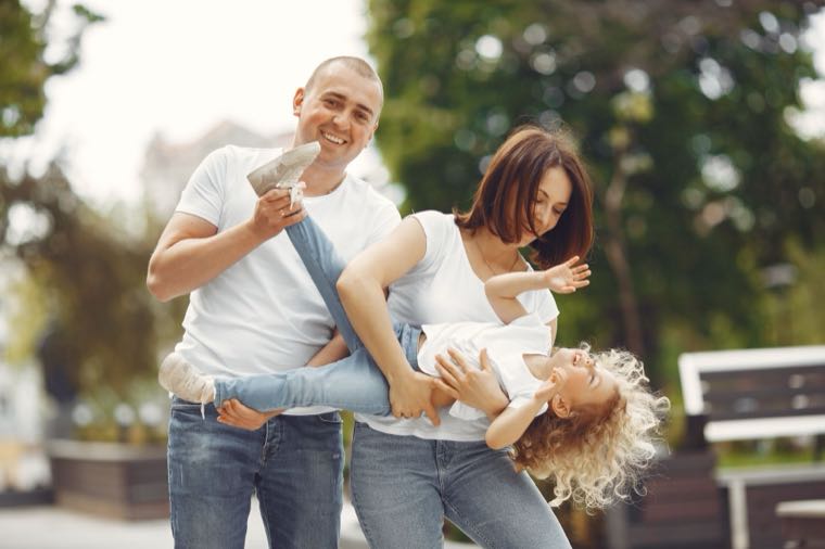 Parents playing outdoors with their child, representing Family Tax Benefit in Australia
