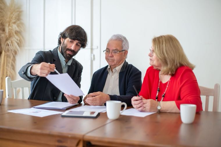 An adviser discussing documents with an older couple, representing choosing a financial adviser
