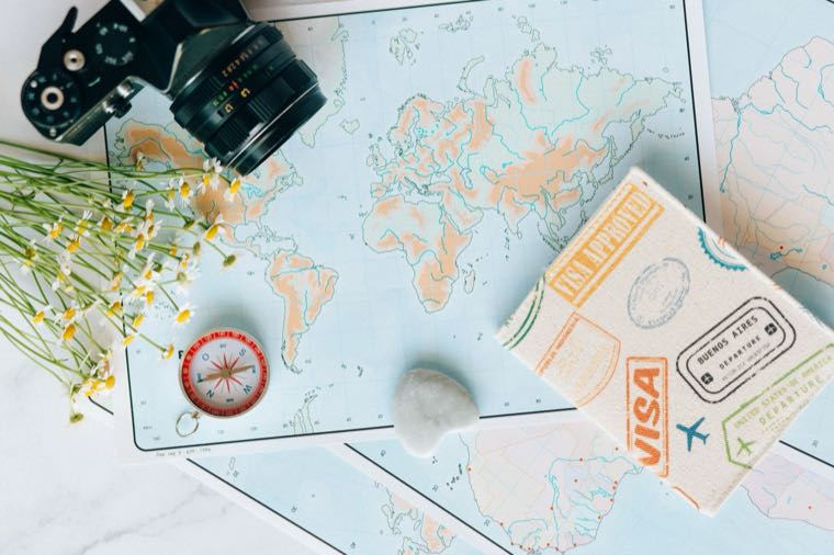 A flat lay of travel essentials including a map and camera, planning a trip from Australia