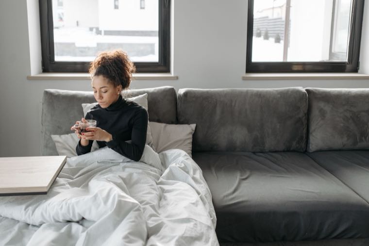 A person resting unwell on a sofa with tea, representing sick leave in Australia