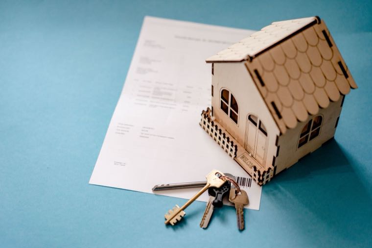 A model house with keys and a contract, representing tax on rental income